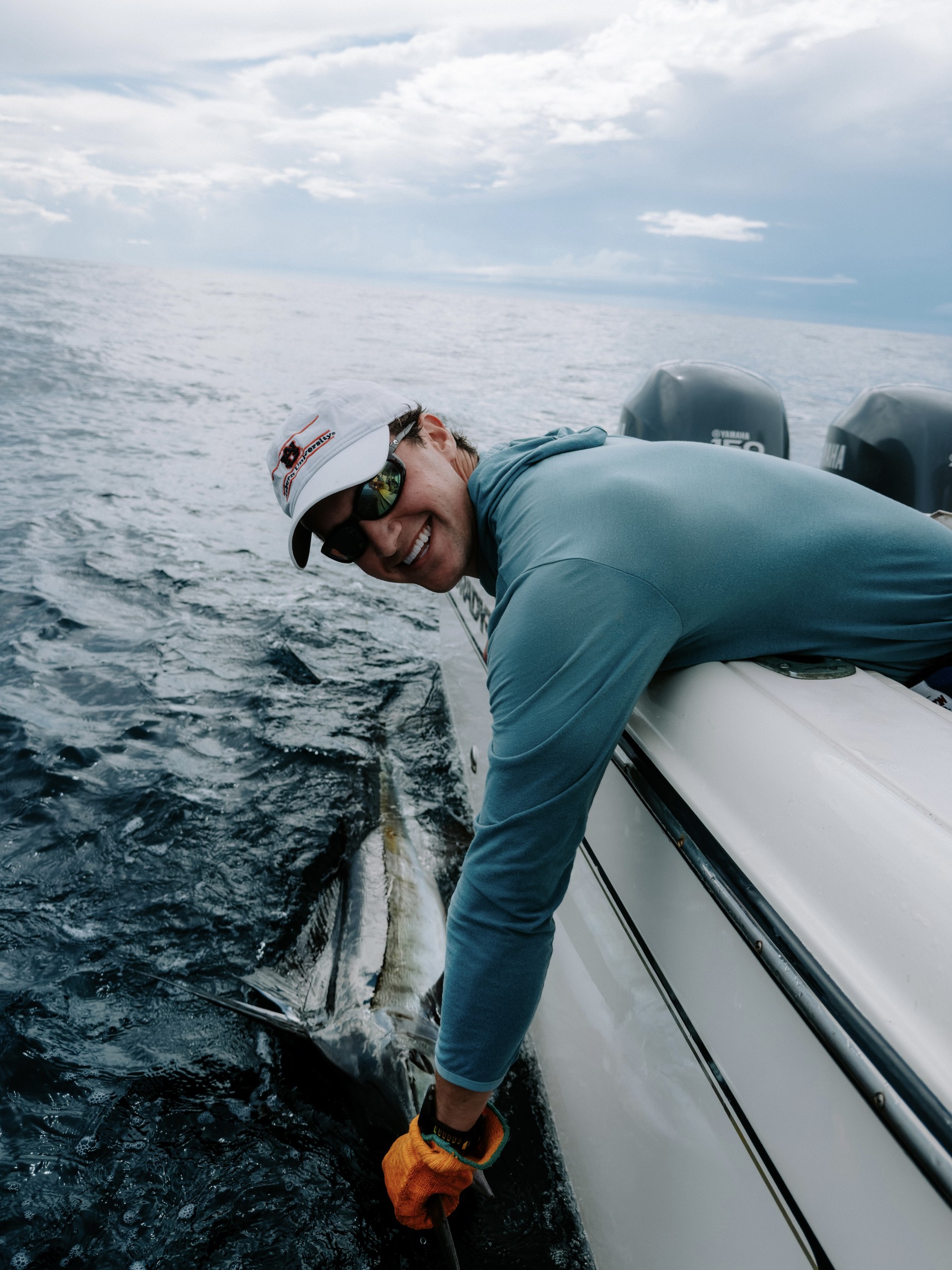 Andrew Carrie releasing a fish beside a boat offshore