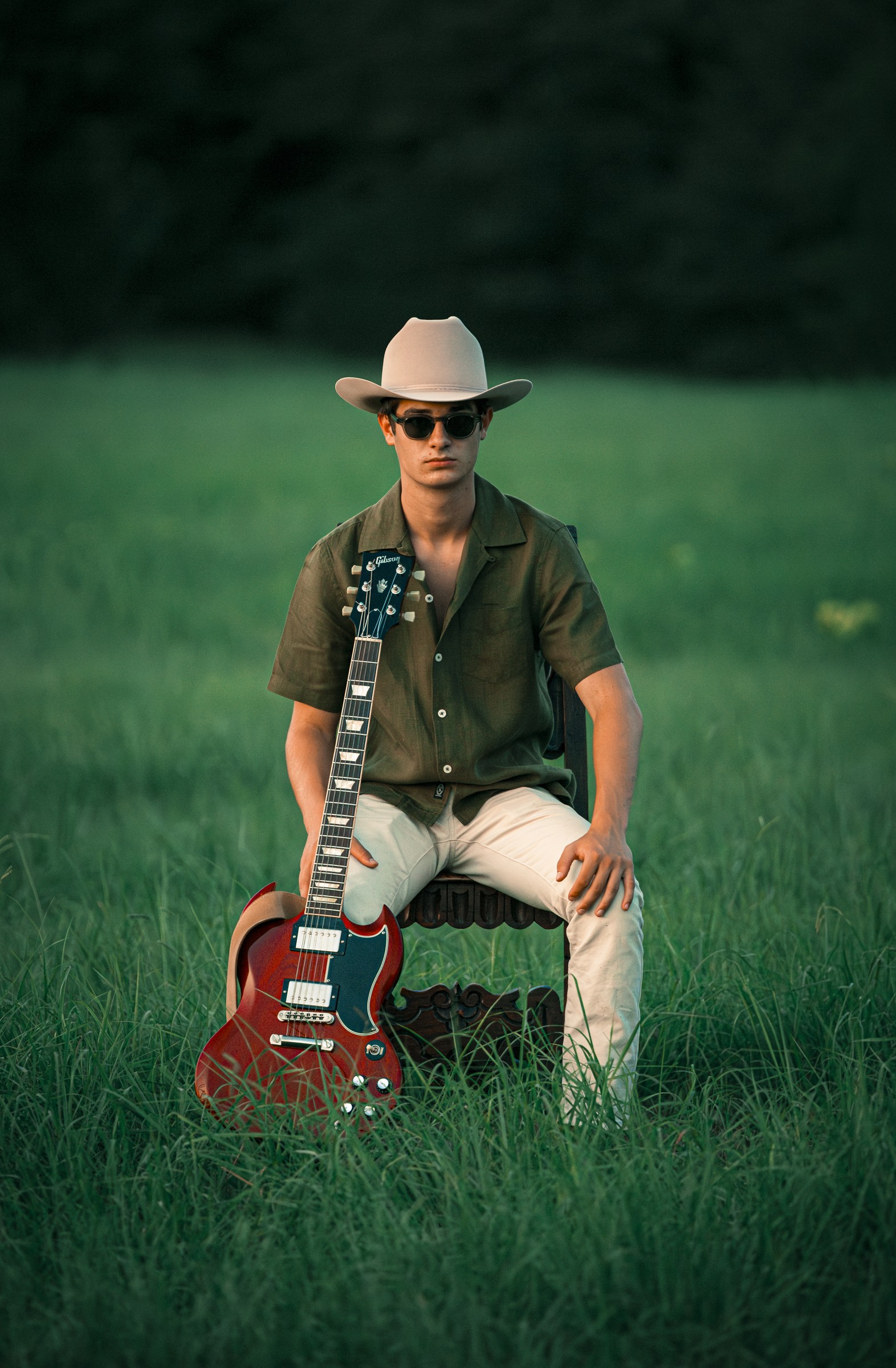 Andrew Carrie seated in a field with his guitar