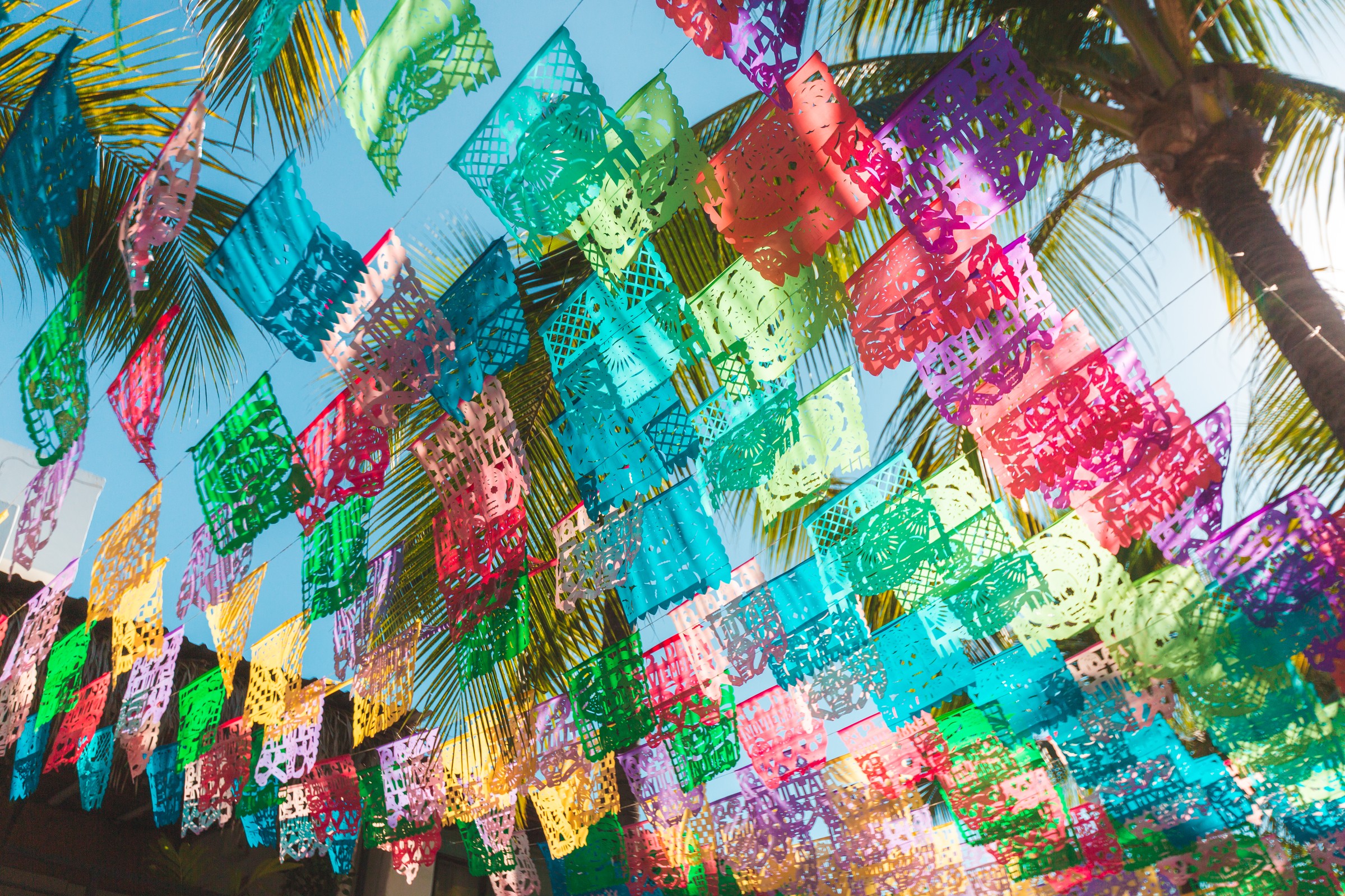Colorful papel picado banners strung beneath palm trees
