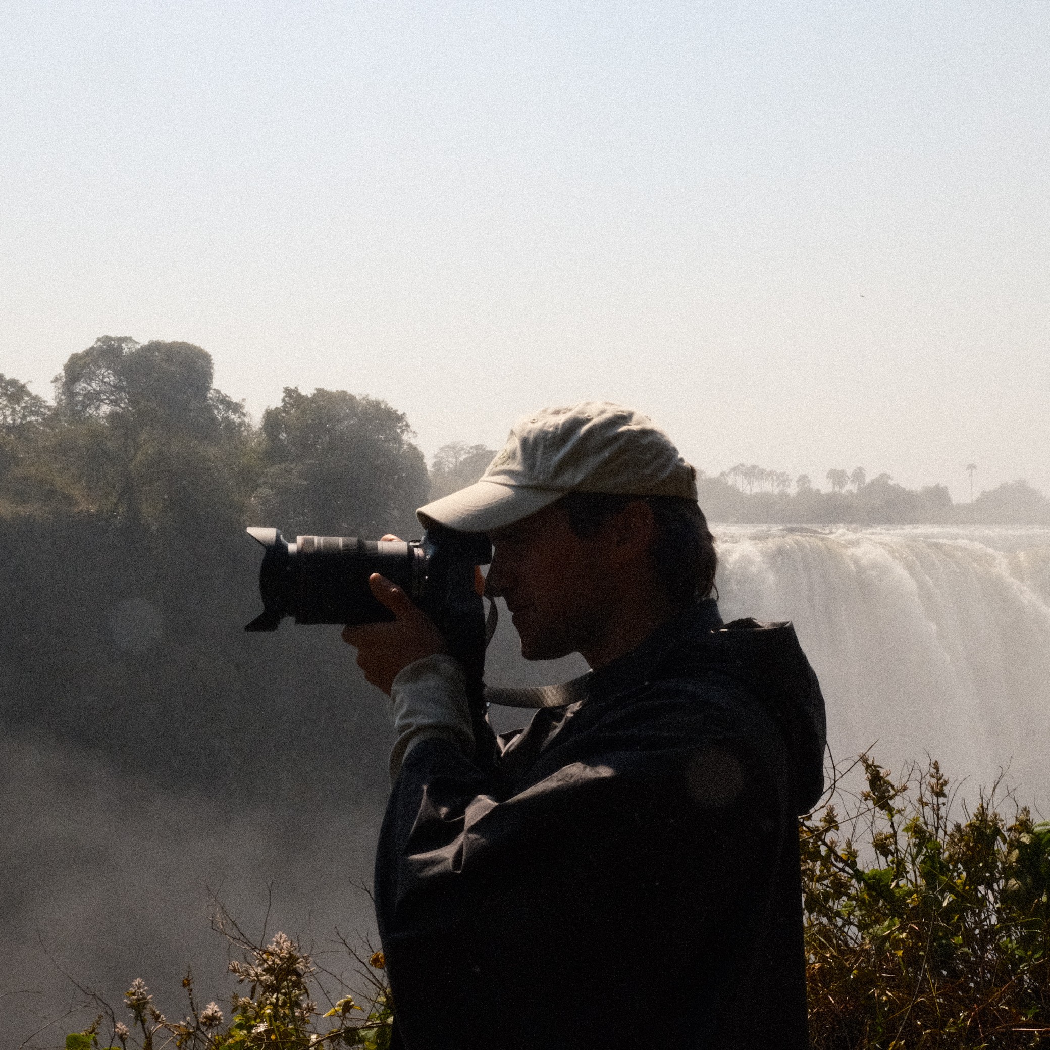 Andrew Carrie photographing at Victoria Falls, spray rising from the gorge behind him